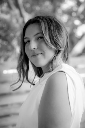 Black and white portrait of woman in white top with soft natural lighting.