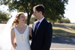 Wedding couple shares a joyful moment outdoors under natural sunlight.