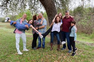 Group of people having fun posing for a playful photo outdoors under a tree.