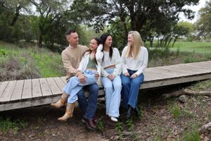 Group sitting casually together on wooden boardwalk surrounded by natural landscape.