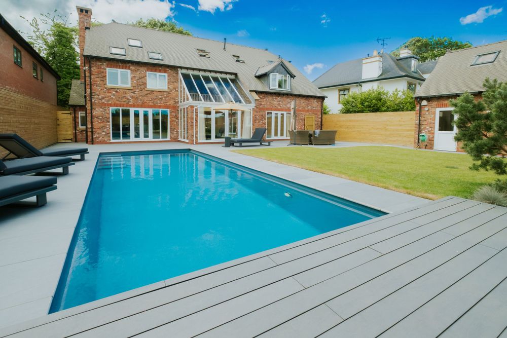 Large brick house with swimming pool and gray composite decking in spacious backyard.