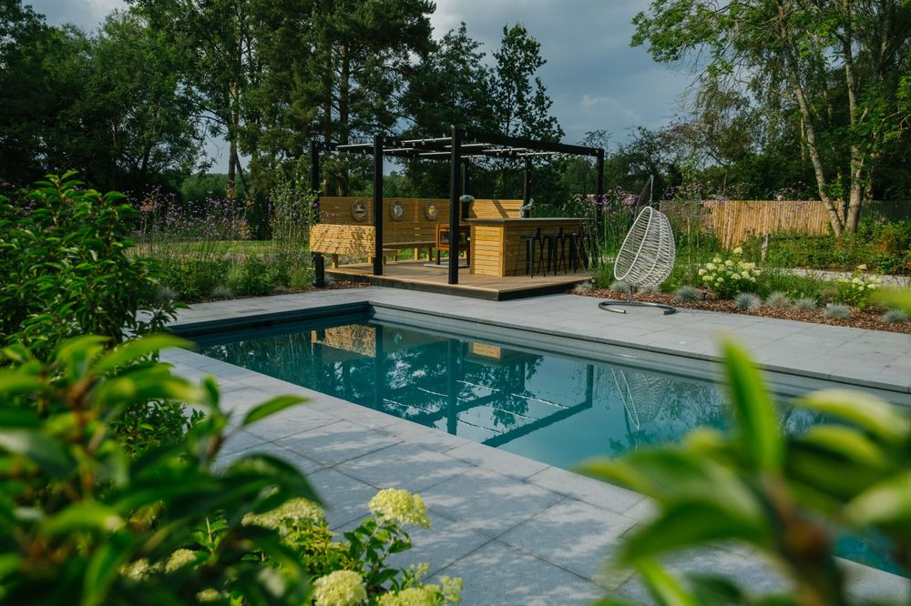 Sleek swimming pool with black pergola and contemporary landscaping in garden setting.