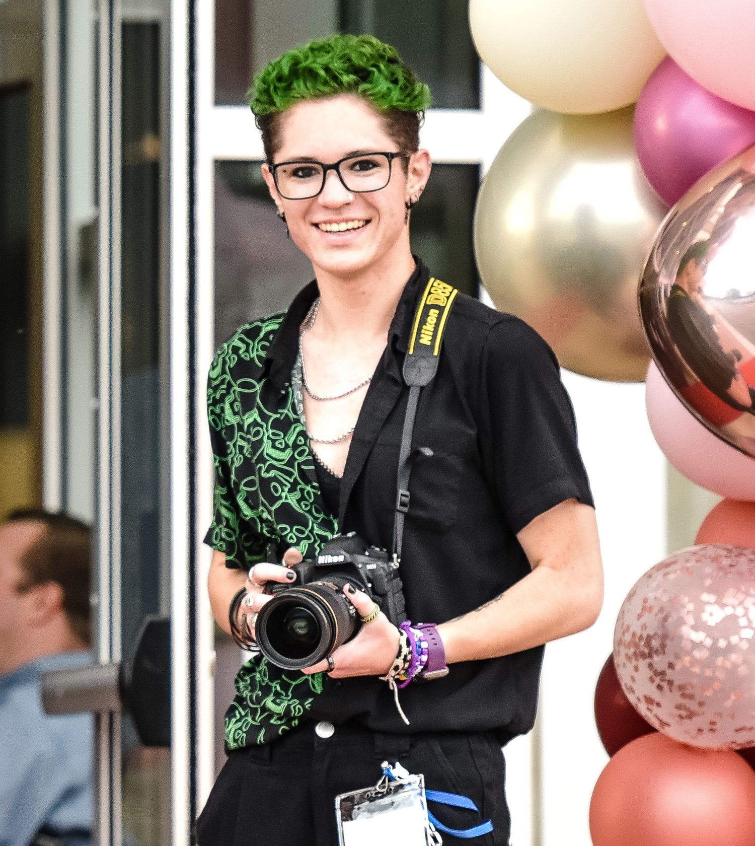 AJ wearing an event badge and holding their camera