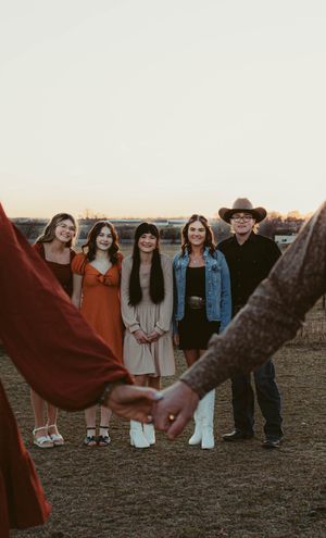 Sunset photoshoot of group in vintage clothing with hands creating frame in foreground.