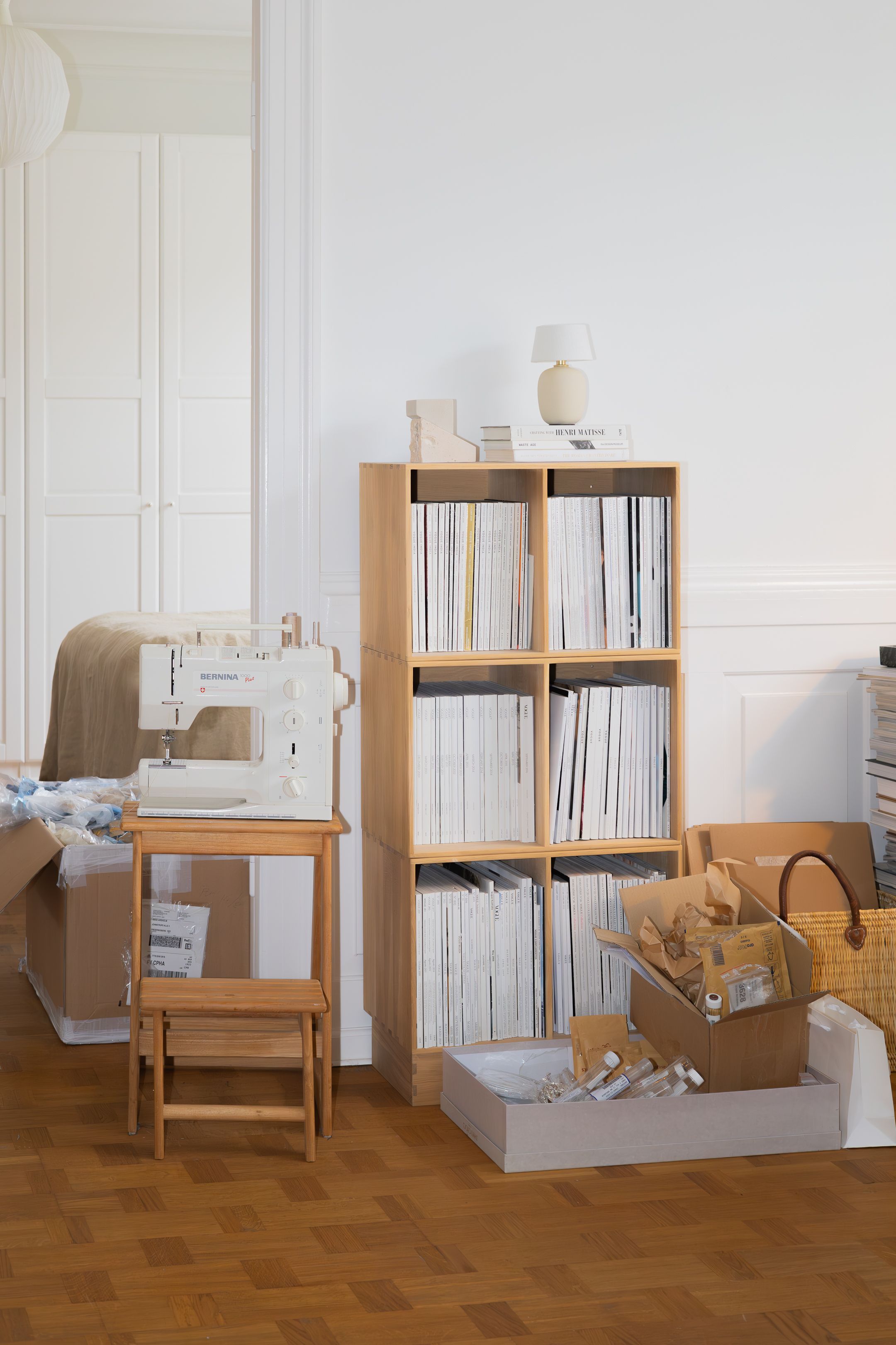 Minimalist craft room with wooden shelving unit, sewing machine and organized storage.