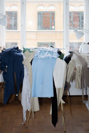 Clothing rack with blue and beige garments displayed in front of a window.