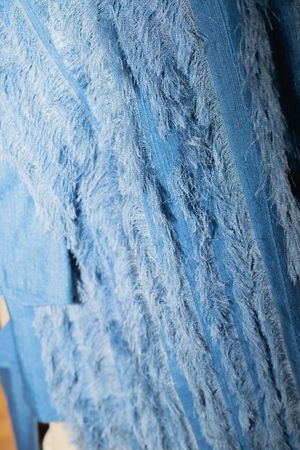 Detailed texture of blue distressed denim fabric with lace overlay.