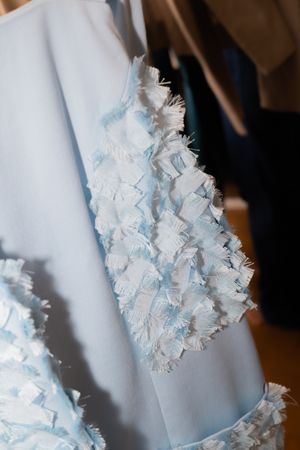 Close-up detail of white textured floral appliques on light blue fabric.