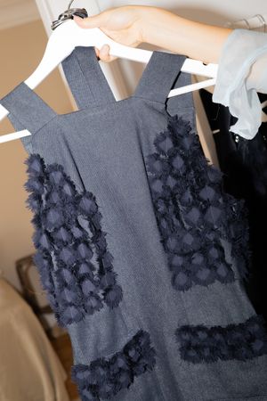 Navy blue dress with delicate lace overlay detailing hanging on white hanger.