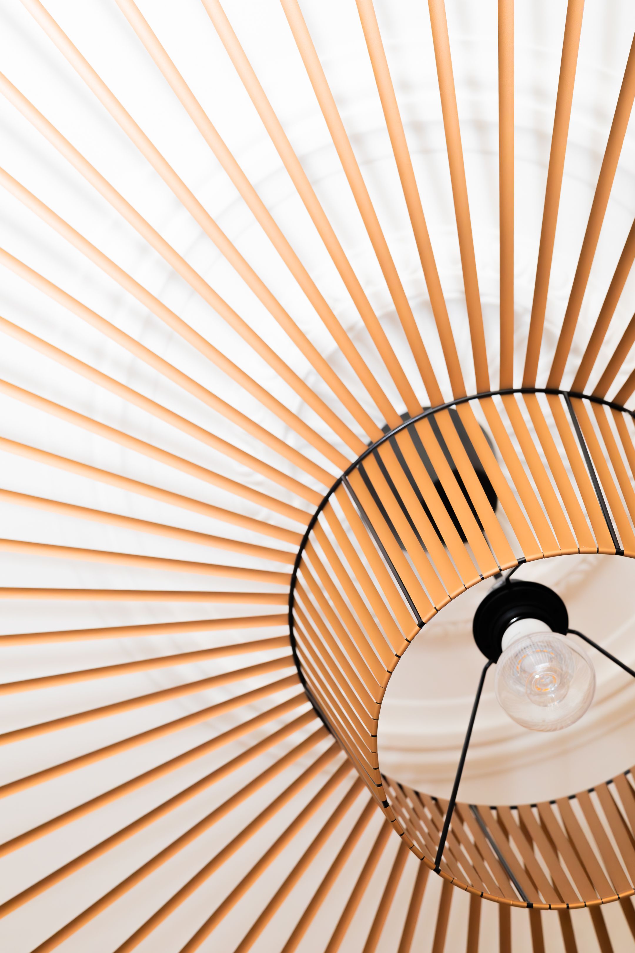 Modern sunburst pattern ceiling lamp with wooden slats creating geometric shadows.