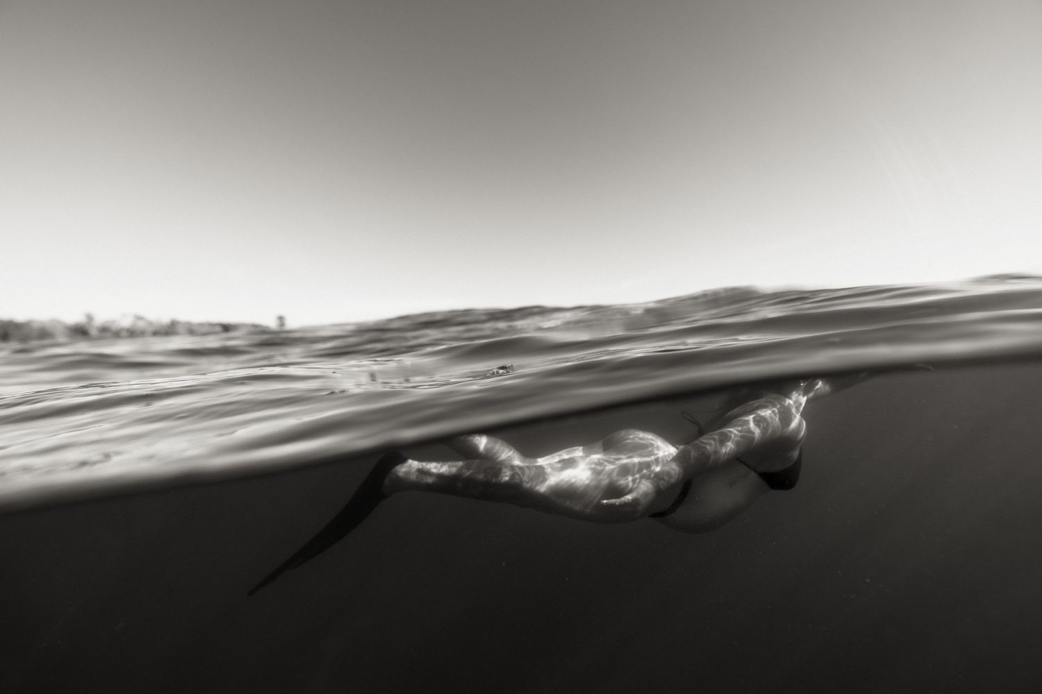 Black and white surfing action photo shot through a tube wave as a surfer rides inside the barrel.