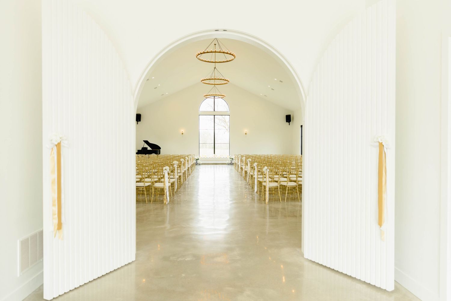 Bright white church interior with arched ceilings and natural light streaming through windows.