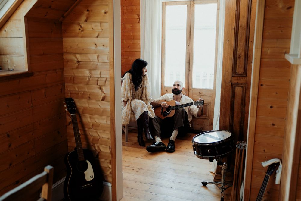 Couple sharing a musical moment in a cozy wooden cabin, man playing acoustic guitar while woman listens nearby.