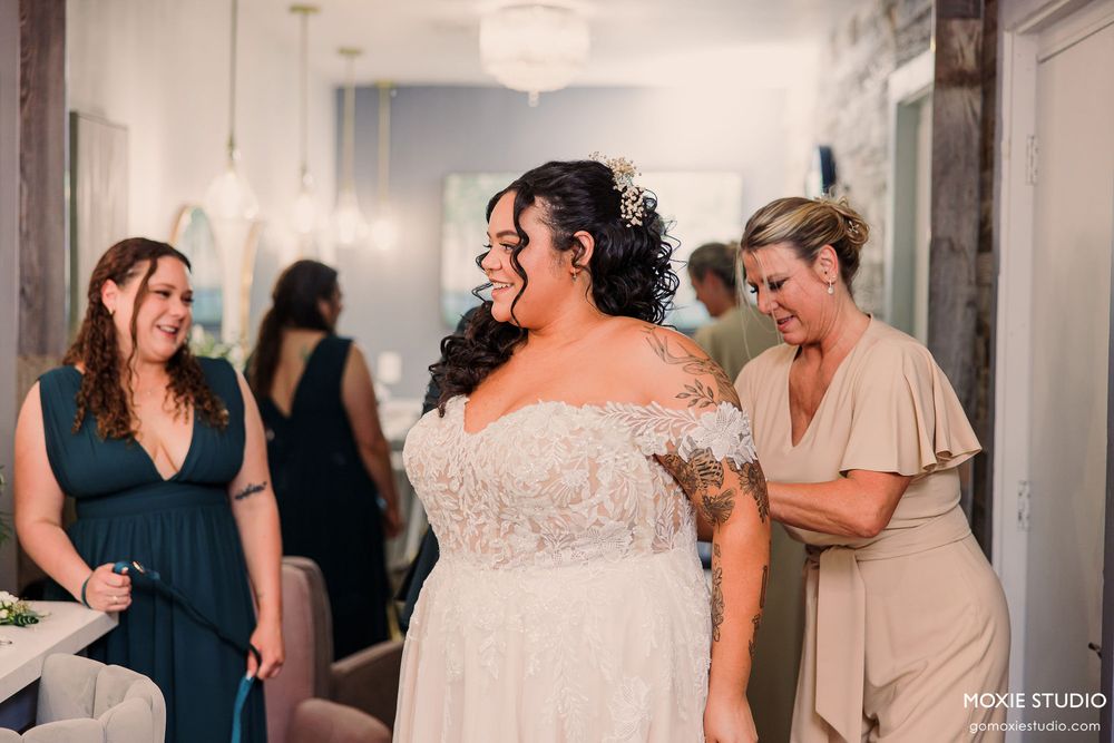 Wedding party celebrates on dance floor at reception with guests in navy blue and neutral colored dresses.