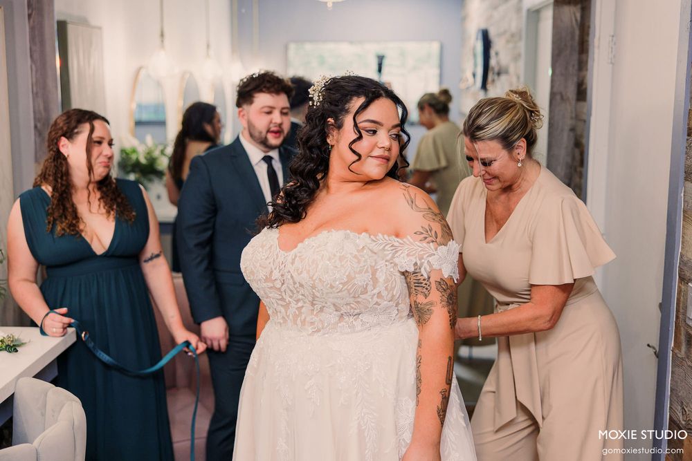 Wedding reception guests in formal attire mingle and celebrate in an elegant indoor venue with white decor.