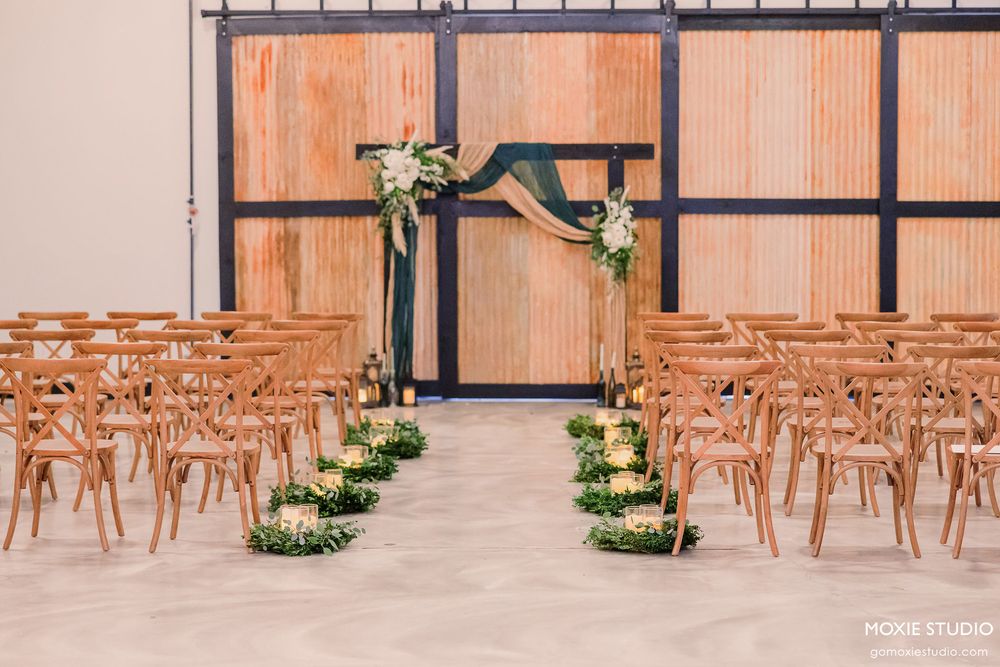 Modern wedding ceremony setup with wooden chairs and minimalist decor against industrial black frames.