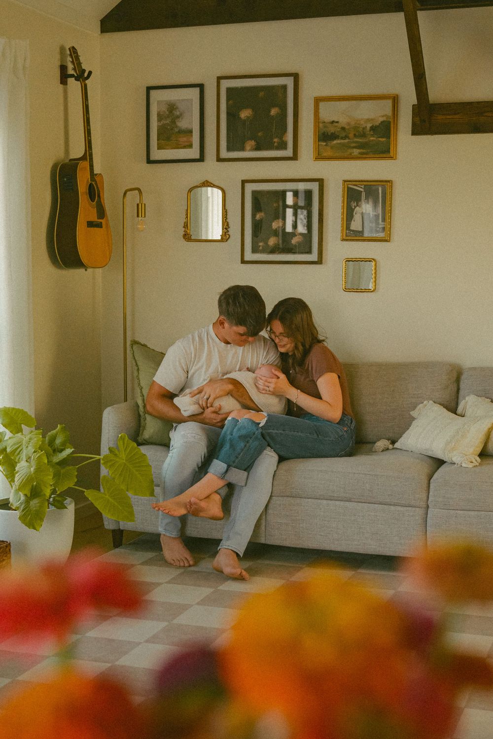 Cozy living room scene with guitar on wall and couple on grey sofa.