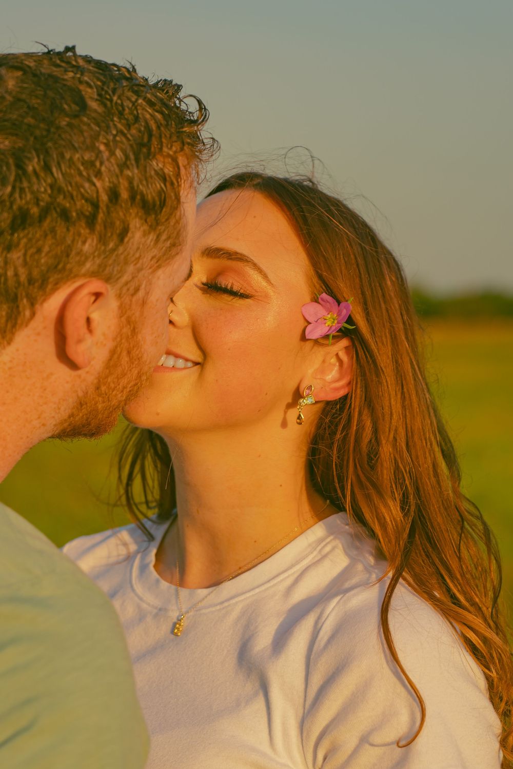 A romantic sunset portrait featuring a pink flower hair accessory.