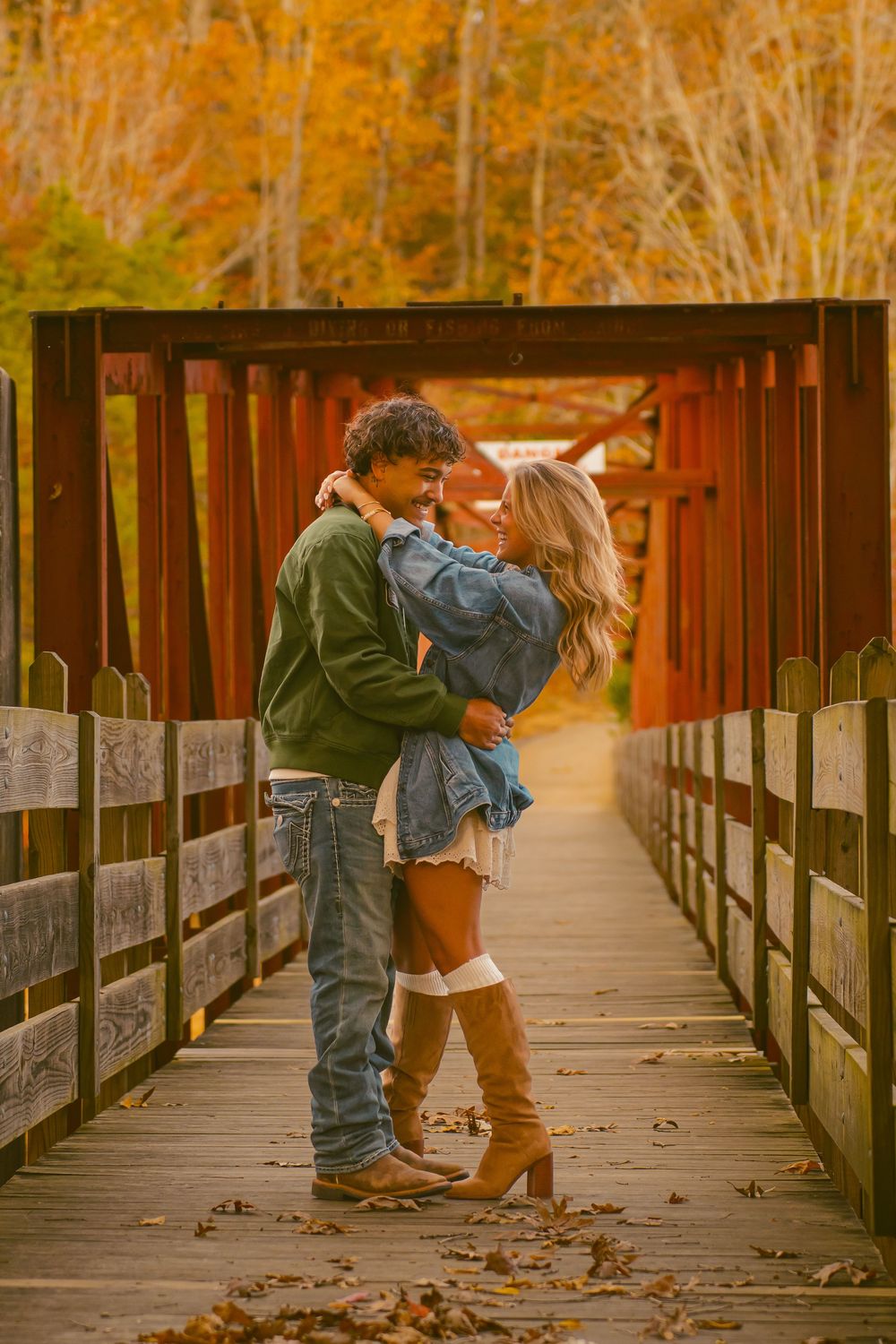 A romantic couple embracing on a wooden bridge during autumn.