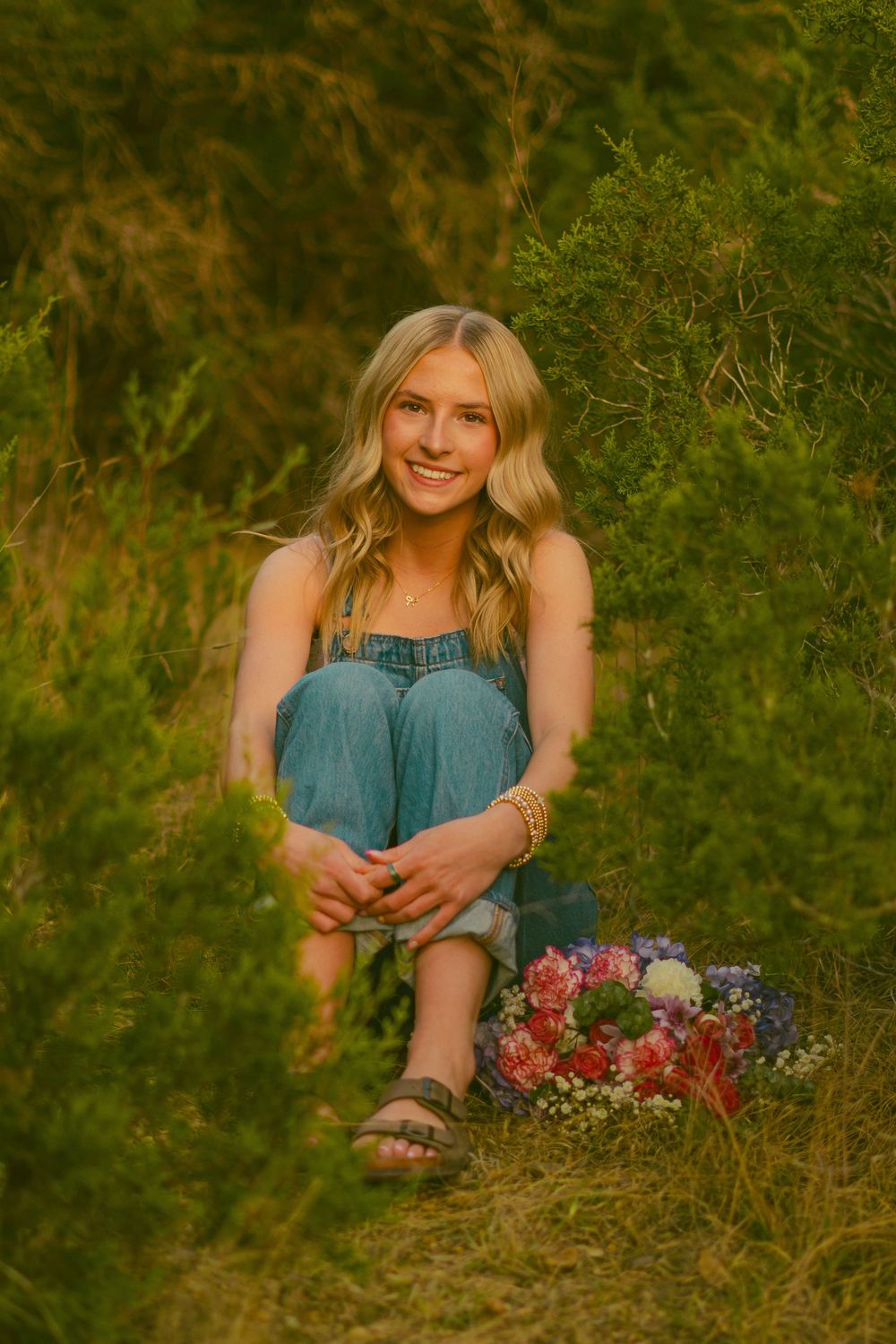 Person relaxes in tall grass with wildflowers during golden hour.
