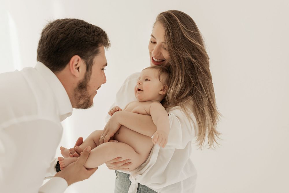 A loving family sharing a tender joyful moment together in a bright minimalist studio setting.