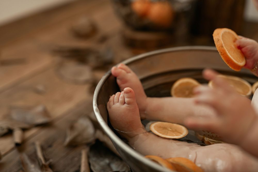 Small slice of orange floating above a silver plate with scattered autumn leaves on a rustic wooden surface.