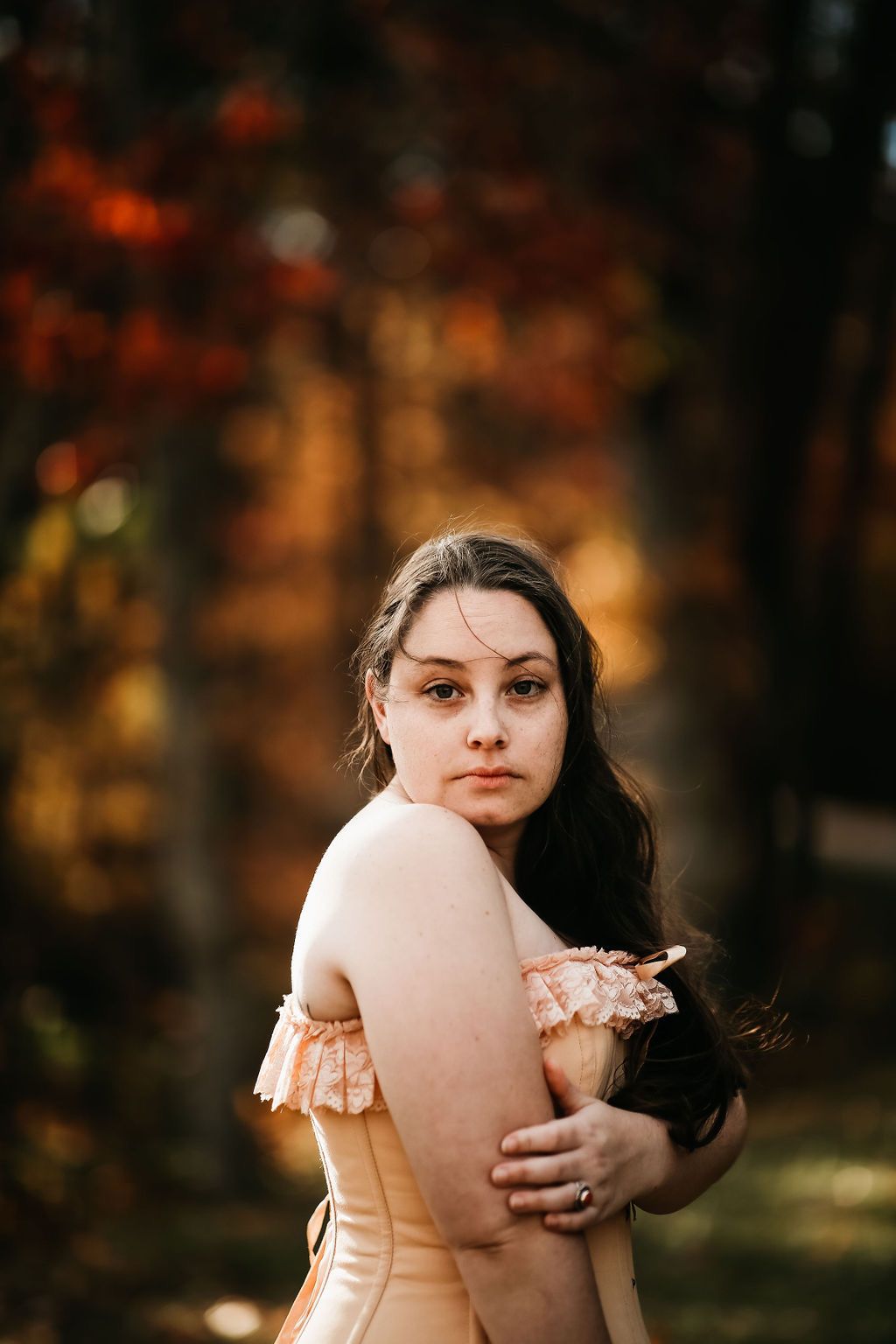 Romantic vintage-inspired portrait with warm autumn colors in forest background.
