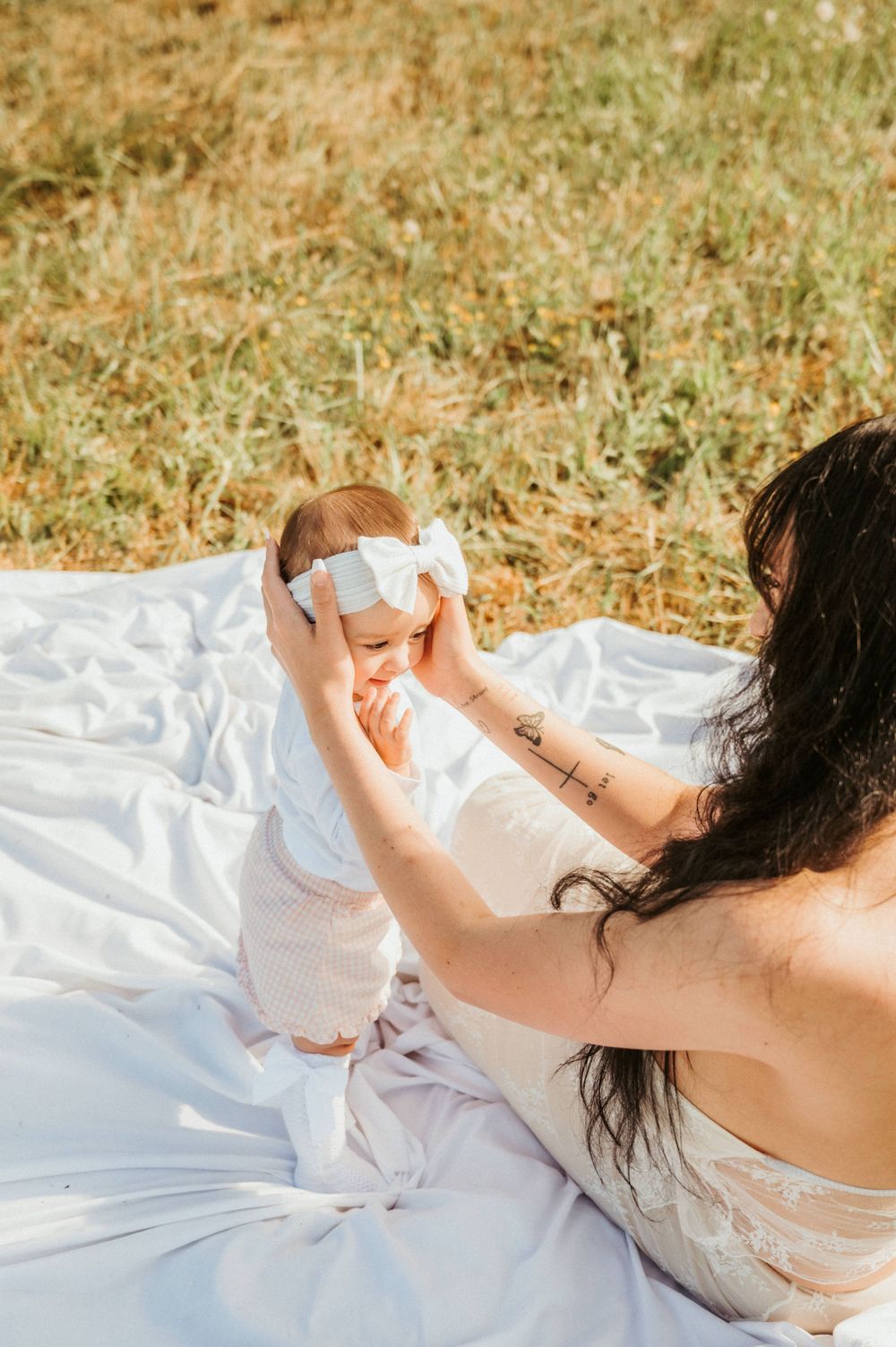 Outdoor family moment on white picnic blanket in sunny meadow.