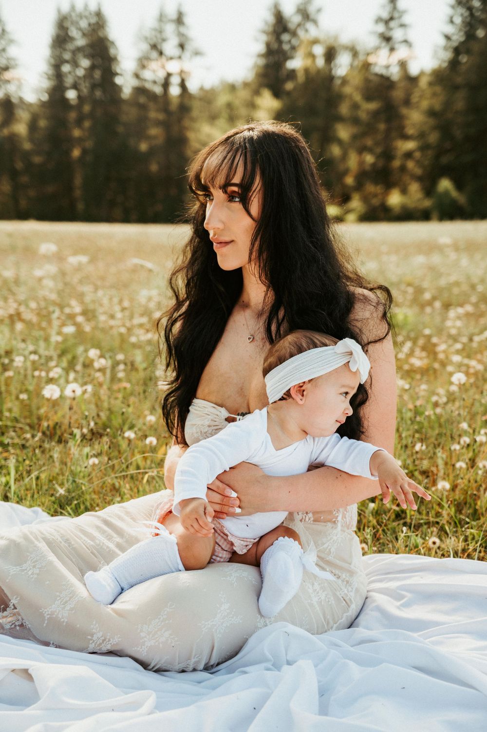 Peaceful outdoor family moment on white blanket in wildflower meadow.