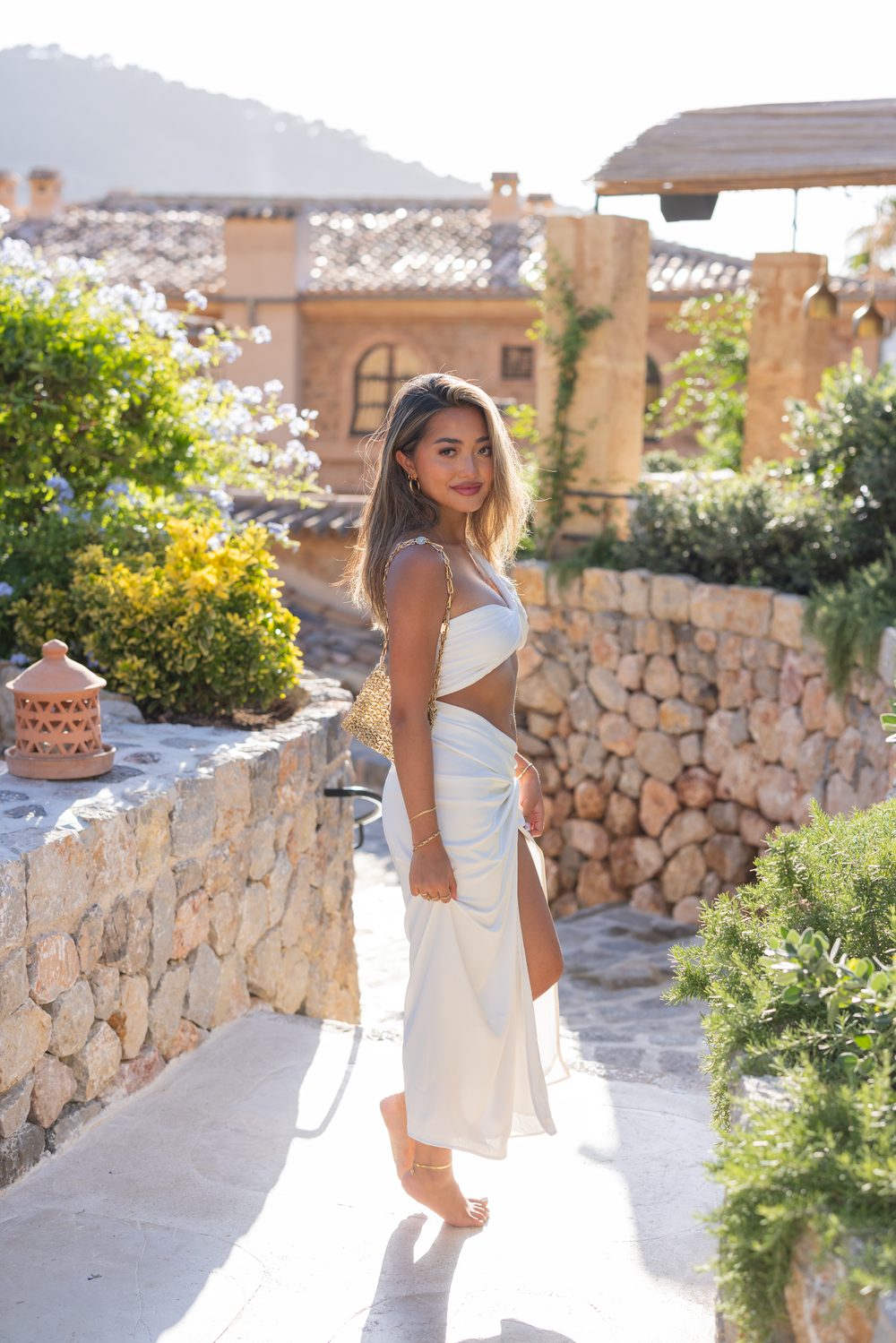 Sun-drenched stone pathway with Mediterranean architecture and lush garden landscaping.