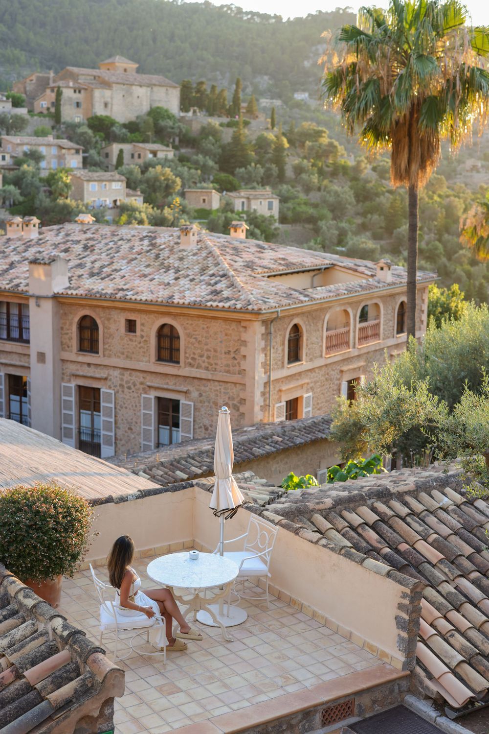 Mediterranean terrace view of stone buildings nestled in hillside during golden hour.