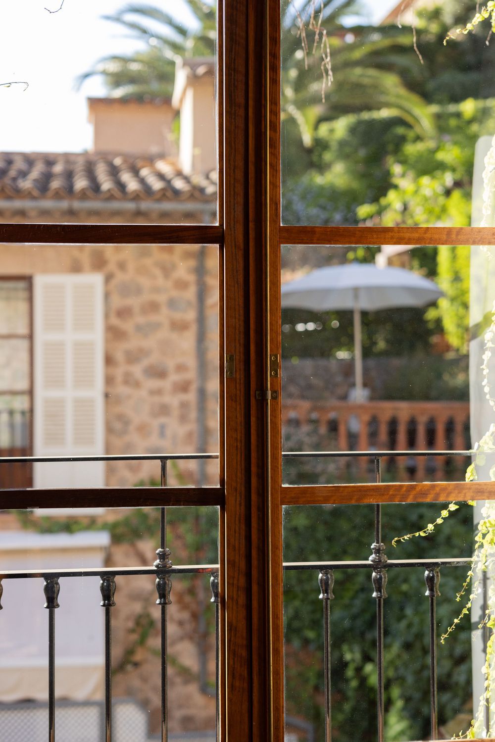 Traditional wooden window frame overlooking Mediterranean architecture and palm trees.