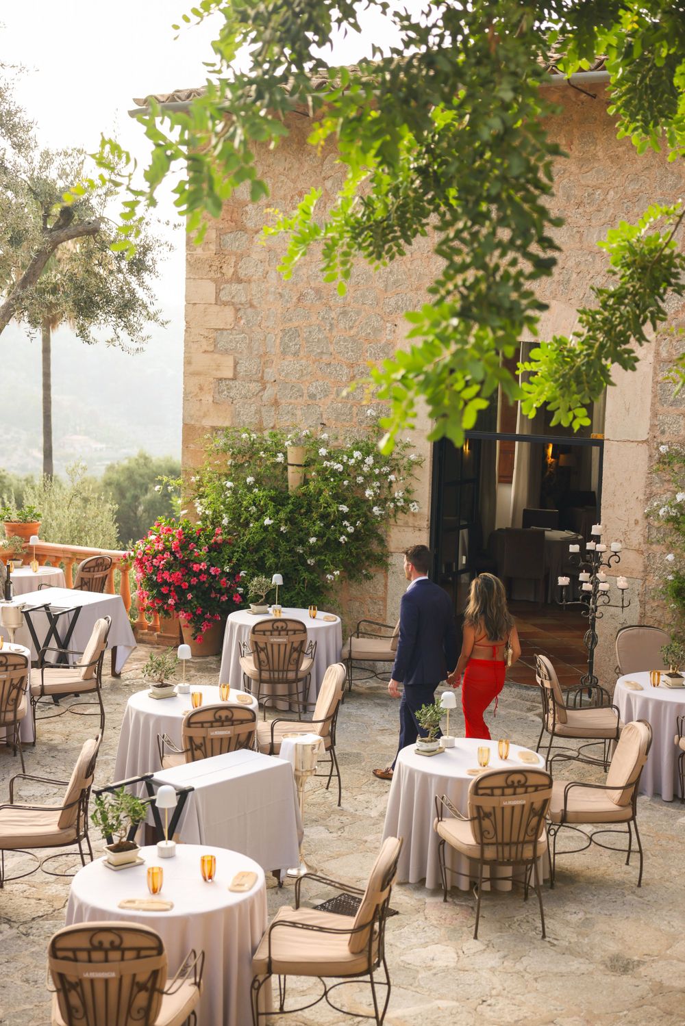 Elegant outdoor dining area with stone walls and white tablecloths at a luxury Mediterranean venue.