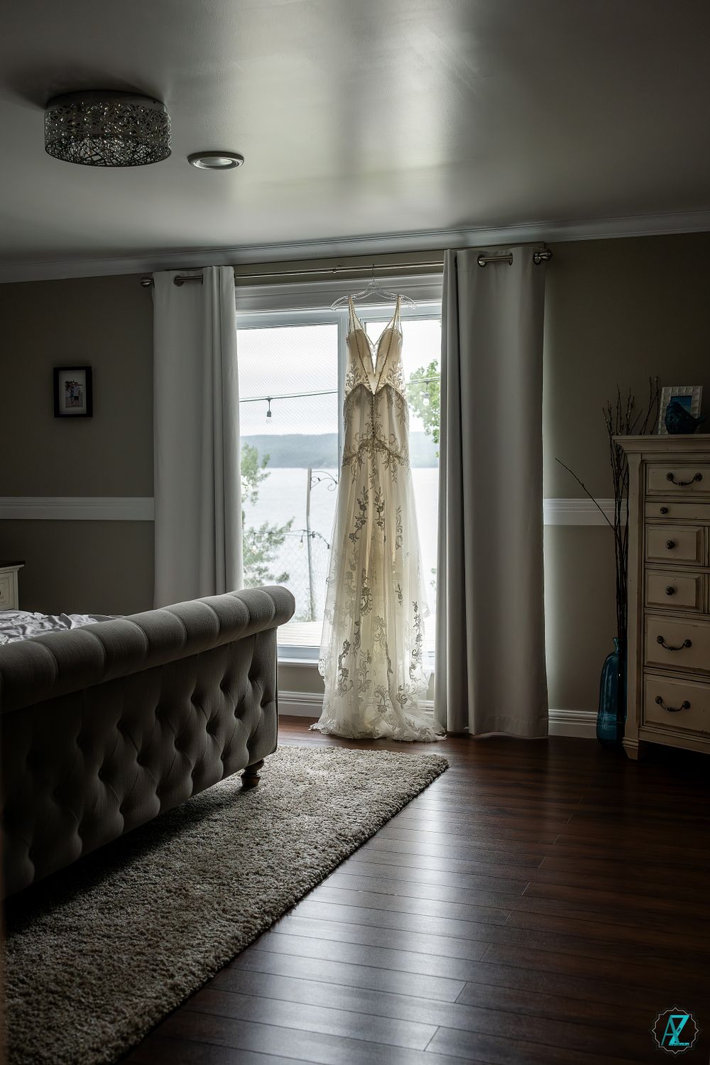 Wedding dress hanging in window with natural light streaming through lace details.