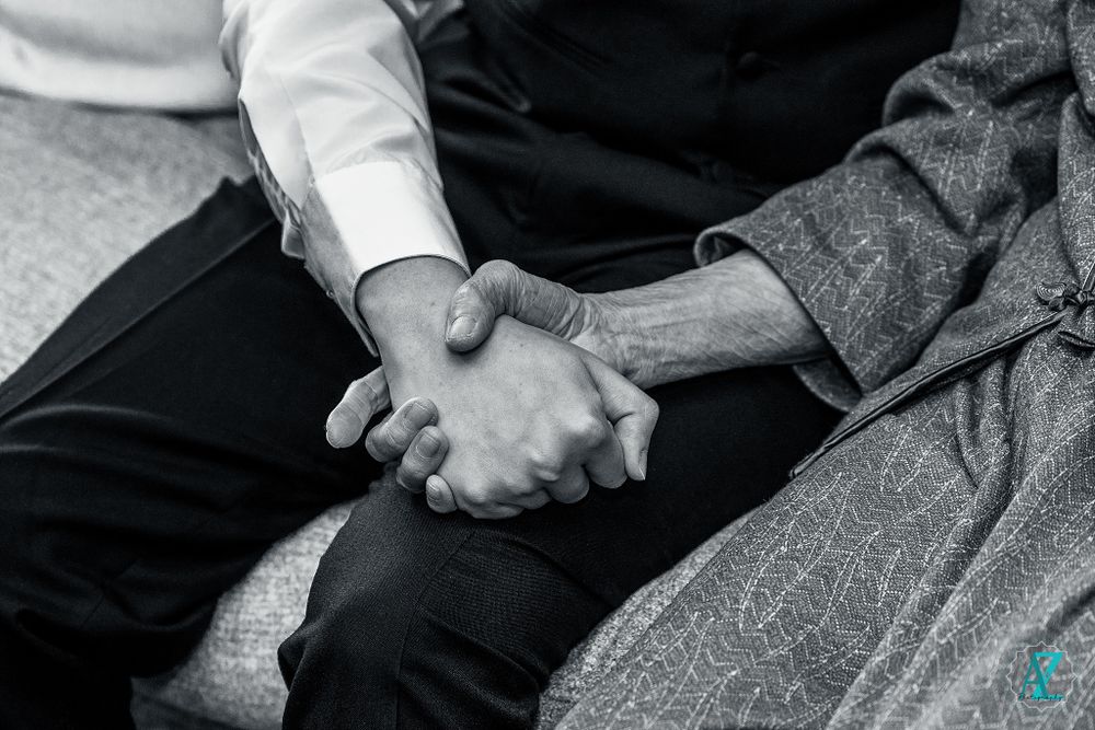 Black and white photo showing two hands clasped together in a moment of connection.