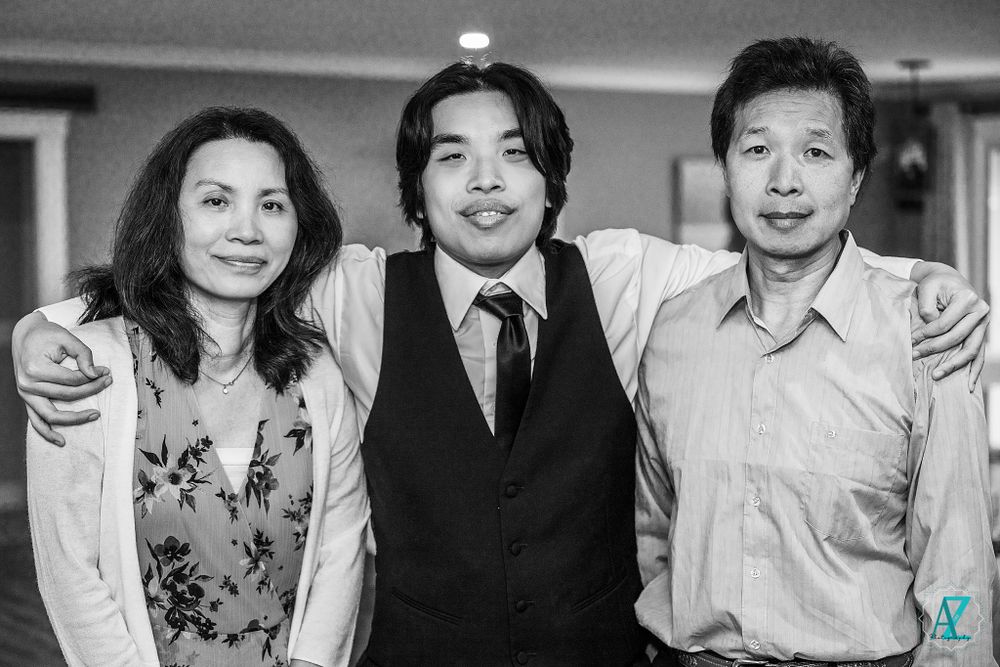 Three people pose together at a formal event in black and white photography.