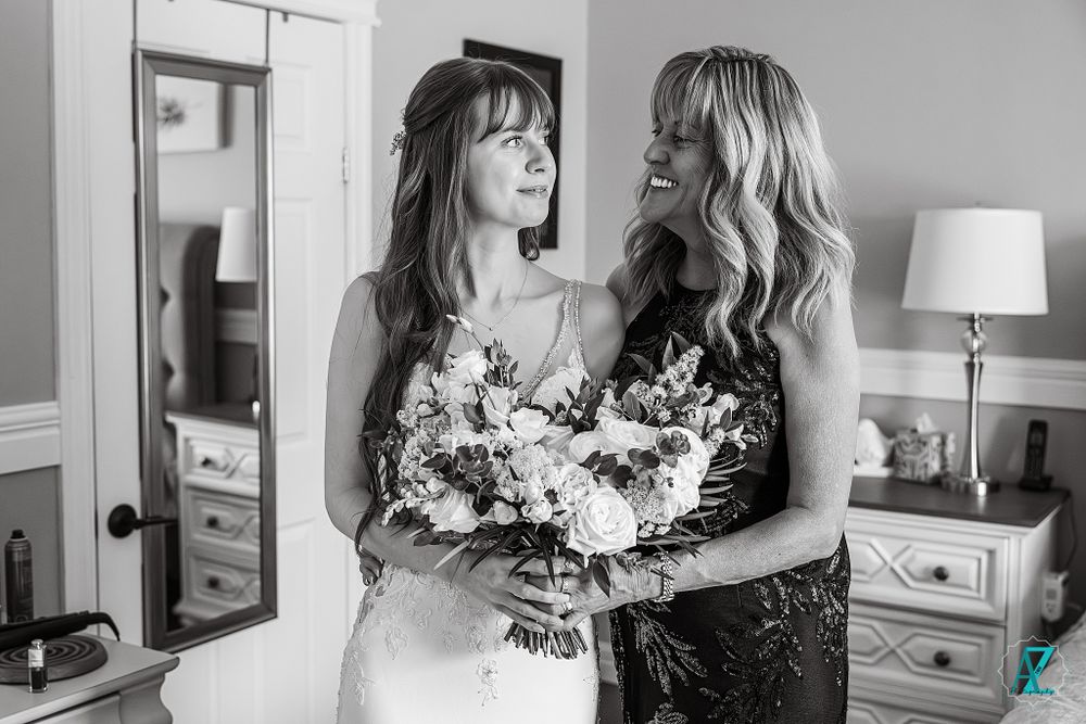 Black and white portrait of two women sharing a joyful moment with a wedding bouquet.