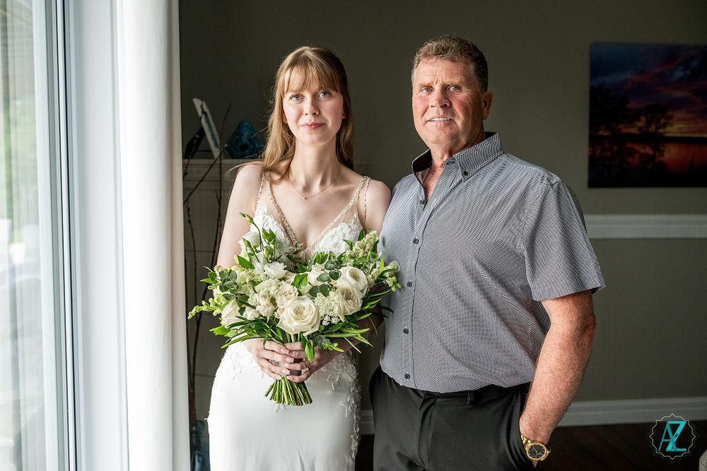 A beautiful wedding portrait by a window featuring an elegant white bouquet.