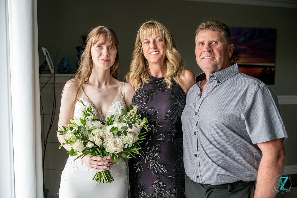 A lovely wedding portrait featuring an elegant white gown and stunning floral arrangement.