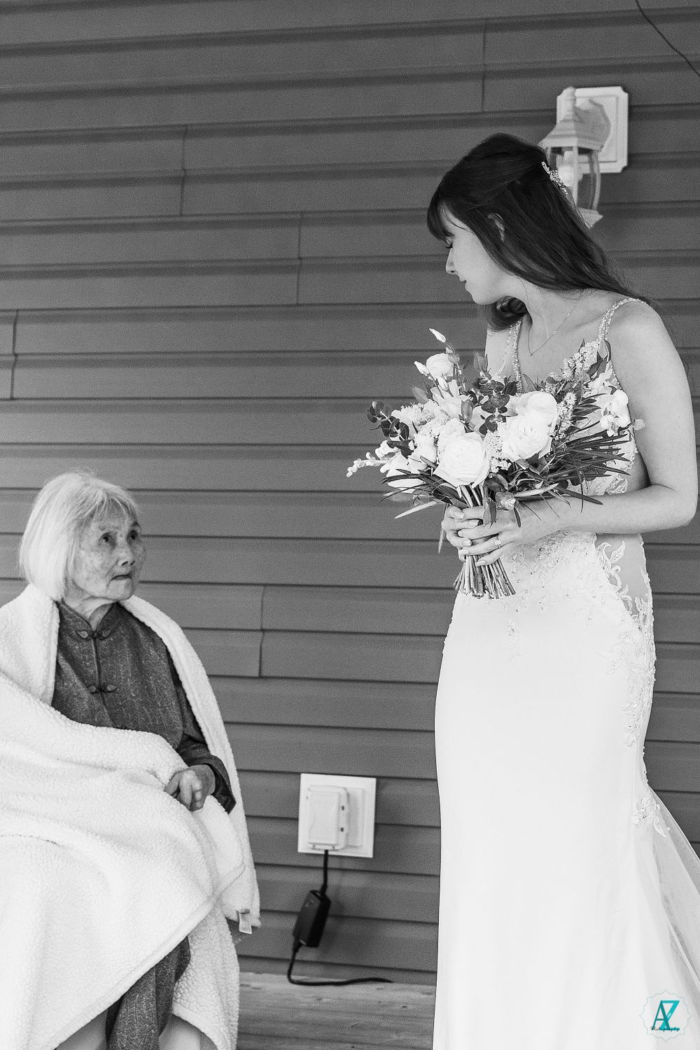 Black and white photo of wedding scene on outdoor porch with elegant floral bouquet.