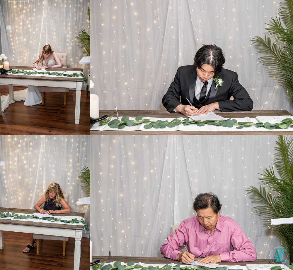 Someone signing documents at a decorated table with twinkling lights in the background.