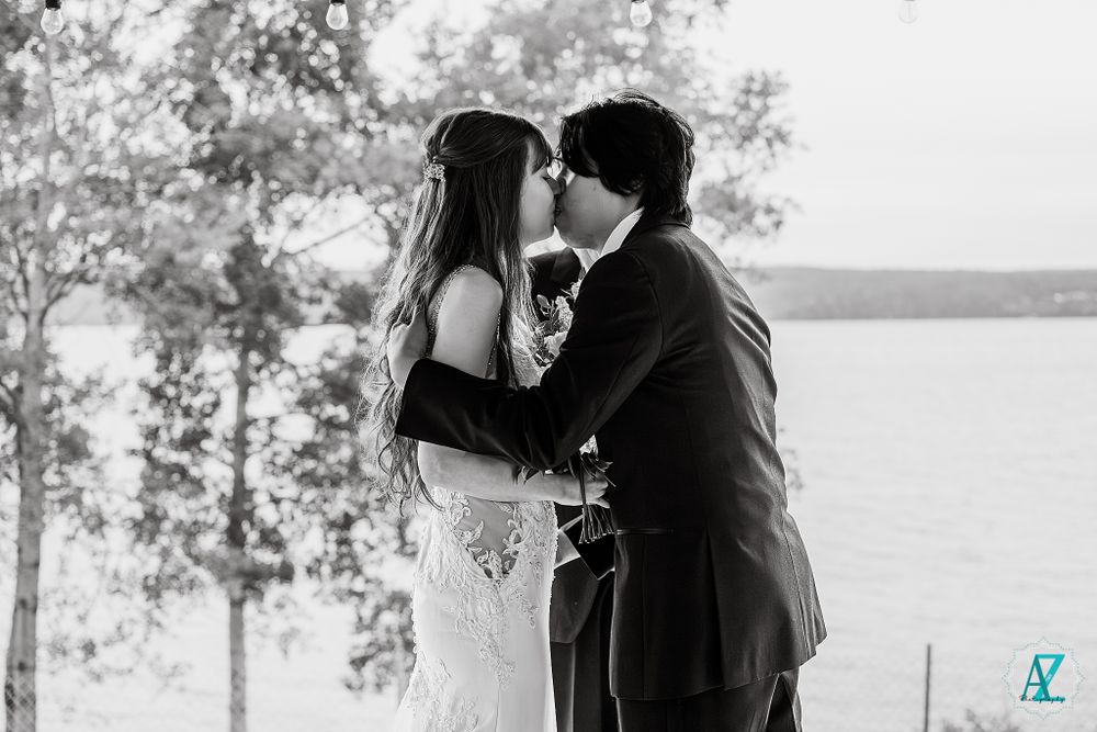 Black and white wedding portrait with scenic lake and trees in the background.