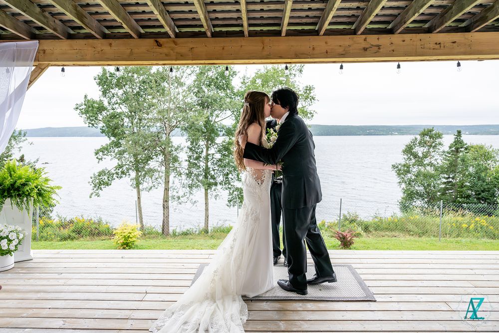 Romantic moment during lakeside wedding ceremony under covered outdoor deck.