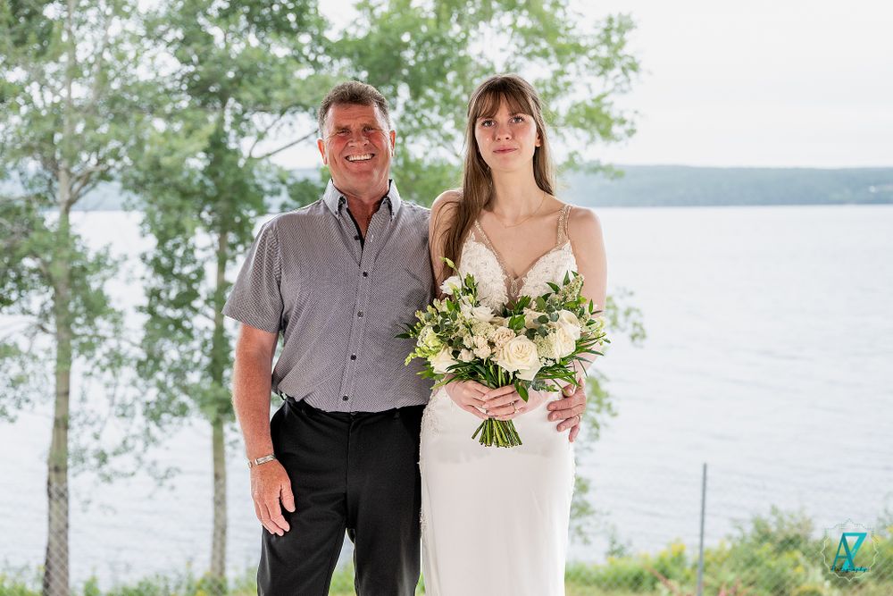 Wedding portrait with lake view featuring elegant white bridal bouquet.