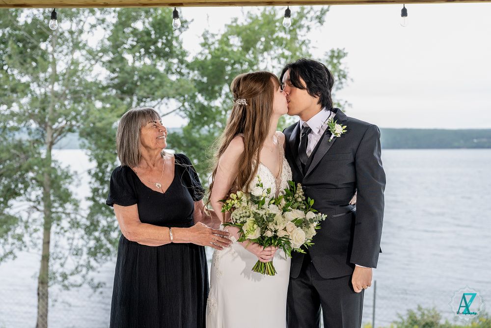 Intimate wedding moment captured on lakeside deck with natural scenery.