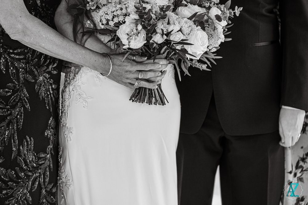 Black and white photo showing hands holding an elegant white and cream bridal bouquet.