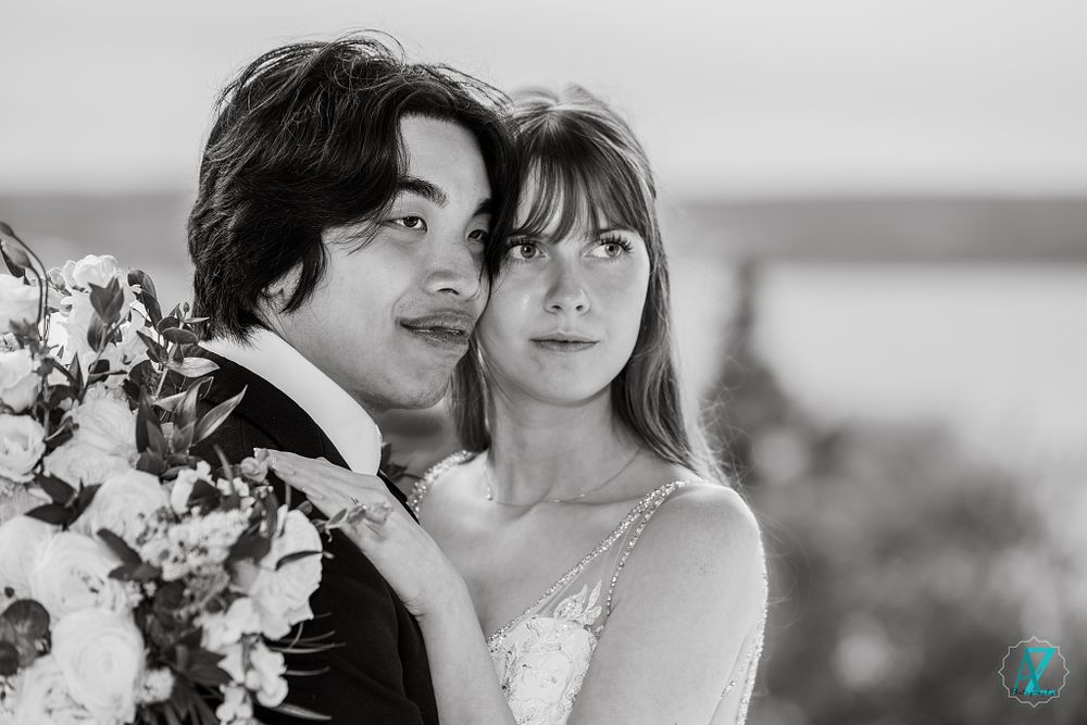 A black and white close-up of newlyweds with the bride holding a floral bouquet.