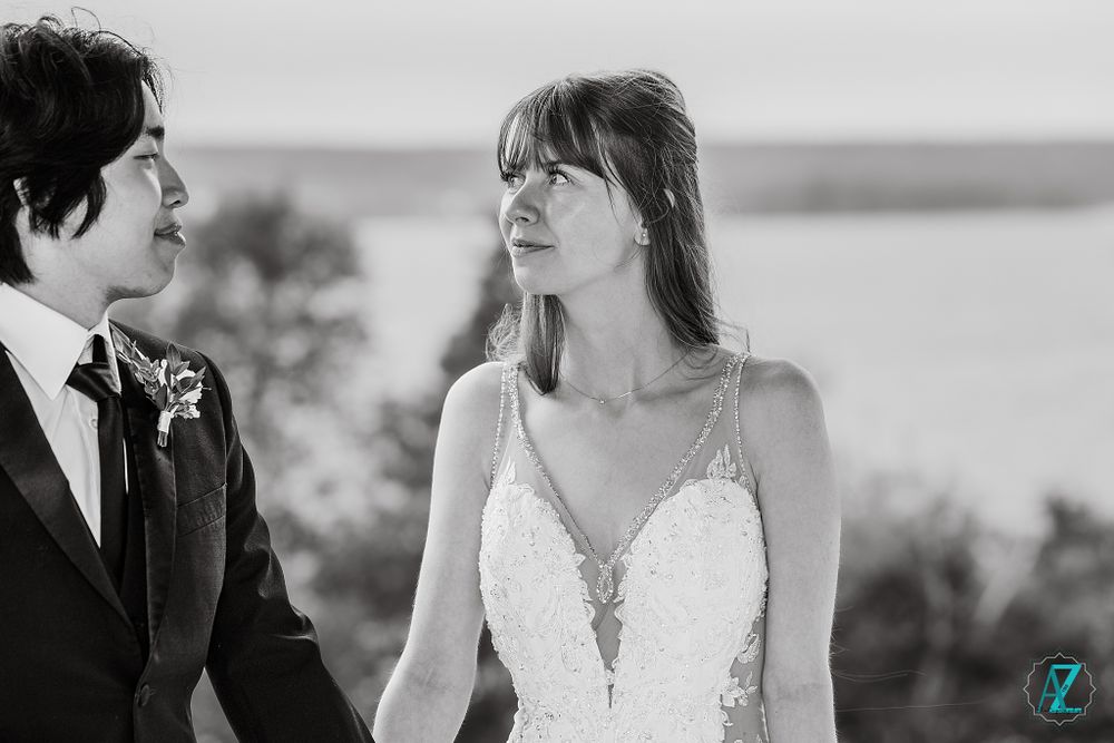 Intimate black and white portrait of newlyweds sharing a tender moment by a lake.
