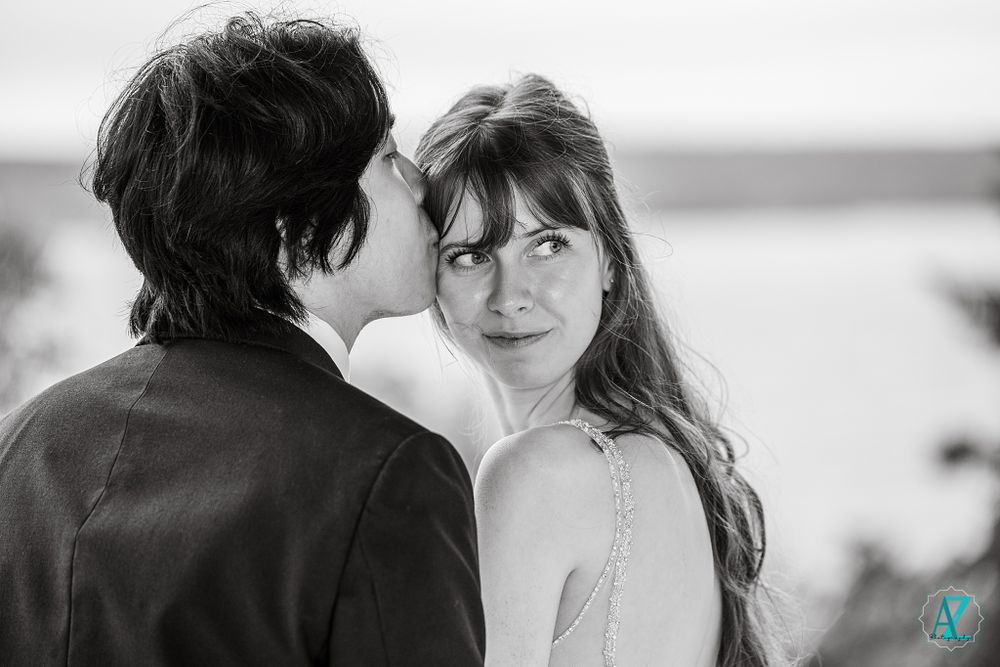 Black and white wedding photo capturing romantic moment between couple by waterfront.