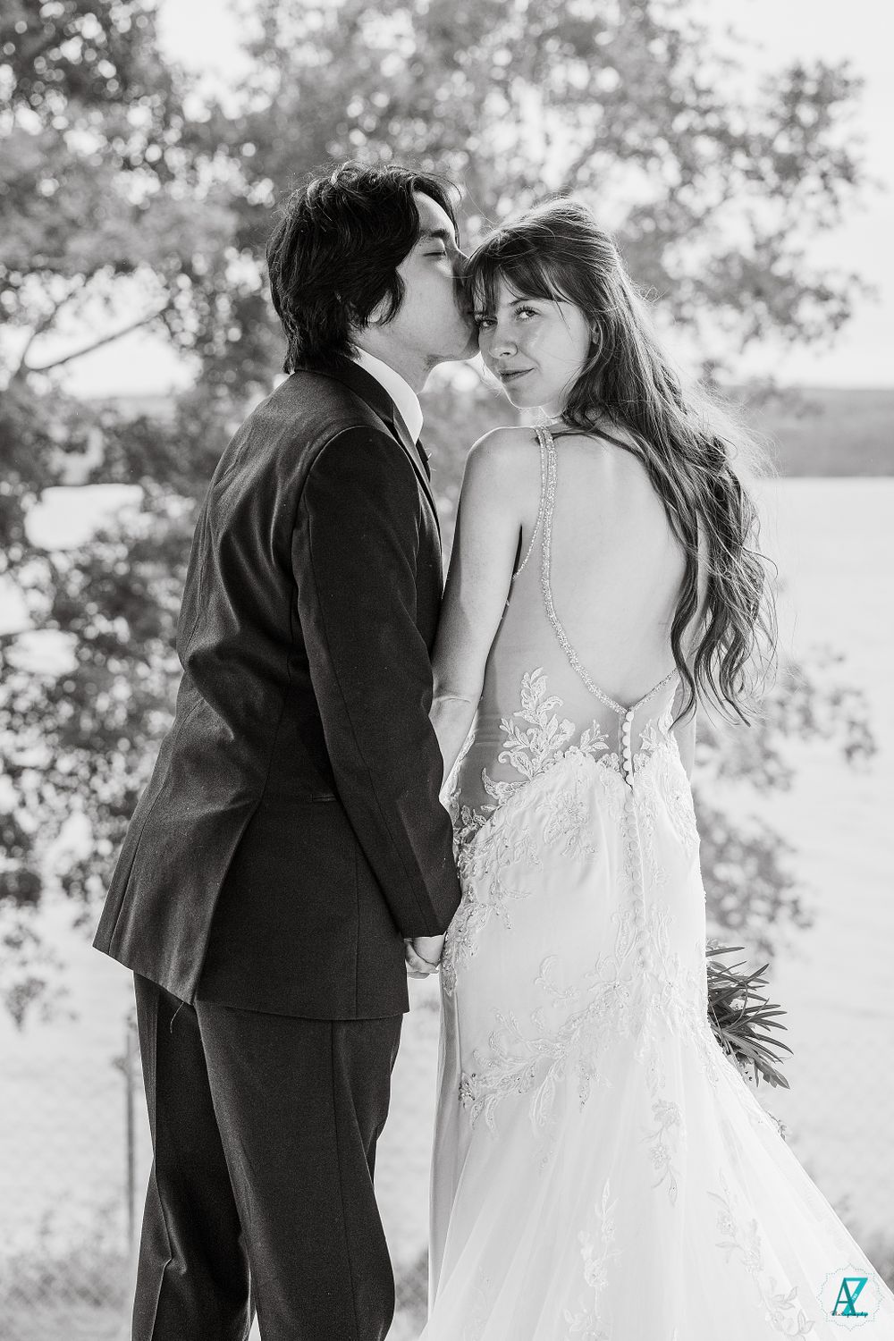 Artistic black and white portrait of wedding couple sharing intimate moment by lake.